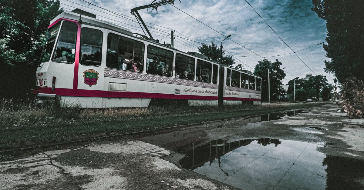 Best way to leave EU with expired visa - Tram riding on railroad near puddles of water and green trees under cloudy sky Best way to leave EU with expired visa - Tram riding on railroad near puddles of water and green trees under cloudy sky