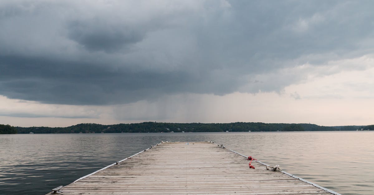 Best way to obtain a Schengen visa for Ukrainian citizen in Canada - Long berth from wooden boards leading to deep water place against terrain covered with trees and houses under cloudy sky with coming rain Best way to obtain a Schengen visa for Ukrainian citizen in Canada - Long berth from wooden boards leading to deep water place against terrain covered with trees and houses under cloudy sky with coming rain