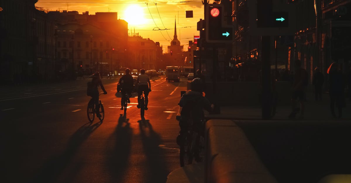 Bike location multi-destination California - Busy street with vehicles driving along asphalt road and pedestrians walking on sidewalk in evening at sundown Bike location multi-destination California - Busy street with vehicles driving along asphalt road and pedestrians walking on sidewalk in evening at sundown
