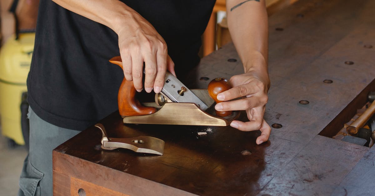 Boarding point change for an Indian rail reservation - Anonymous male carpenter with tattoo adjusting knife in planer for cutting wood during work in professional workshop on blurred background Boarding point change for an Indian rail reservation - Anonymous male carpenter with tattoo adjusting knife in planer for cutting wood during work in professional workshop on blurred background