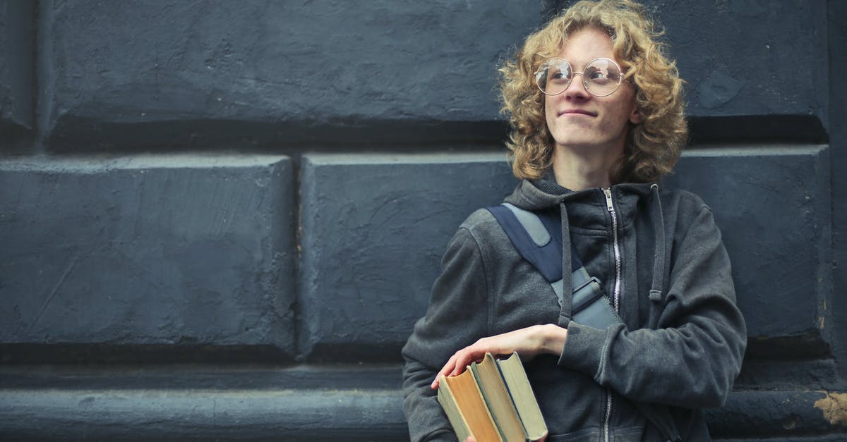 Book Now or Wait [closed] - Young Man Leaning Against The Wall Holding A Books