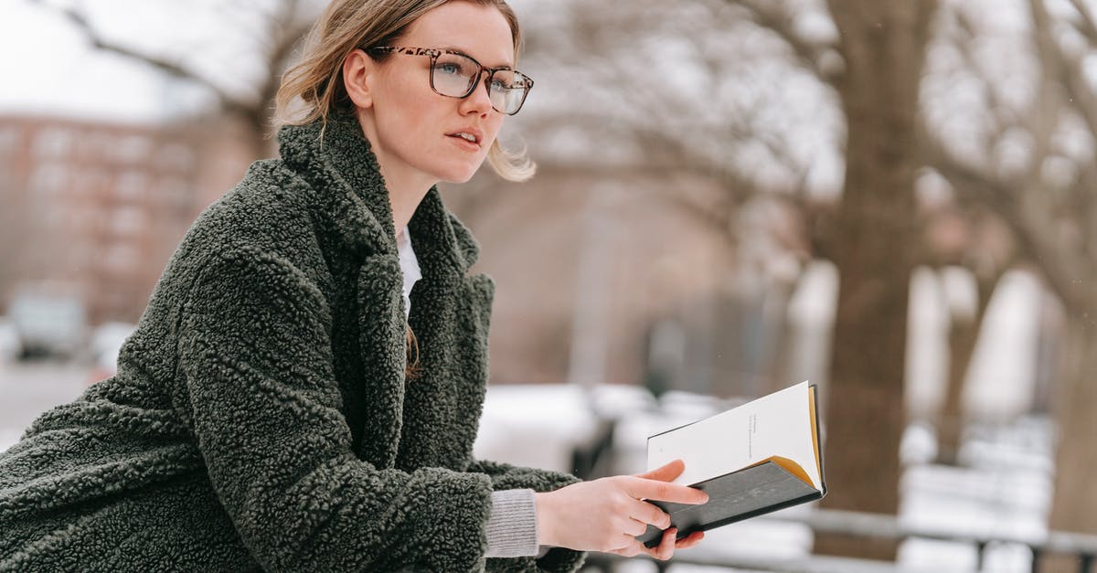 Book Now or Wait [closed] - Young thoughtful woman with open book on street
