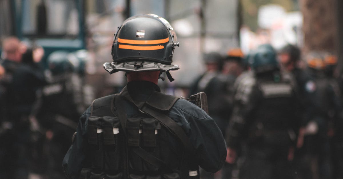 Border control officer asking questions on leaving Canada - Back view of anonymous policeman in helmet and bulletproof vest maintaining law and order while standing on city street Border control officer asking questions on leaving Canada - Back view of anonymous policeman in helmet and bulletproof vest maintaining law and order while standing on city street