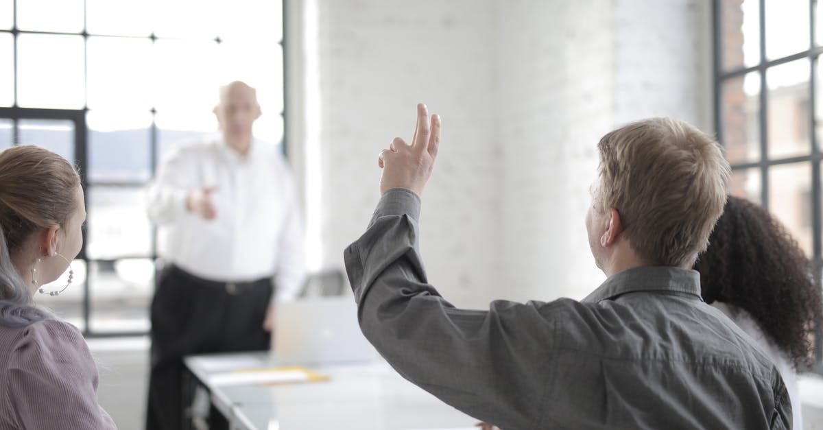 Boss is asking for passport, but it has a stamp in it I don't want him to see. What to do? - Male employee raising hand for asking question at conference in office boardroom