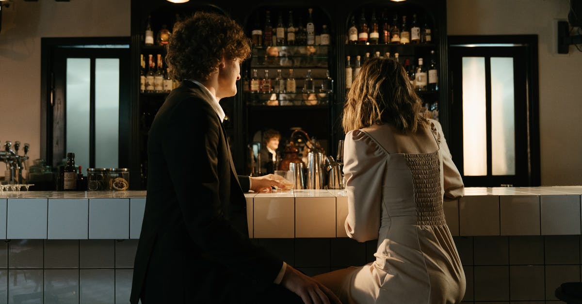 Bringing extra alcohol back to the US: what will it cost? - Man and Woman Sitting on Counter Bringing extra alcohol back to the US: what will it cost? - Man and Woman Sitting on Counter