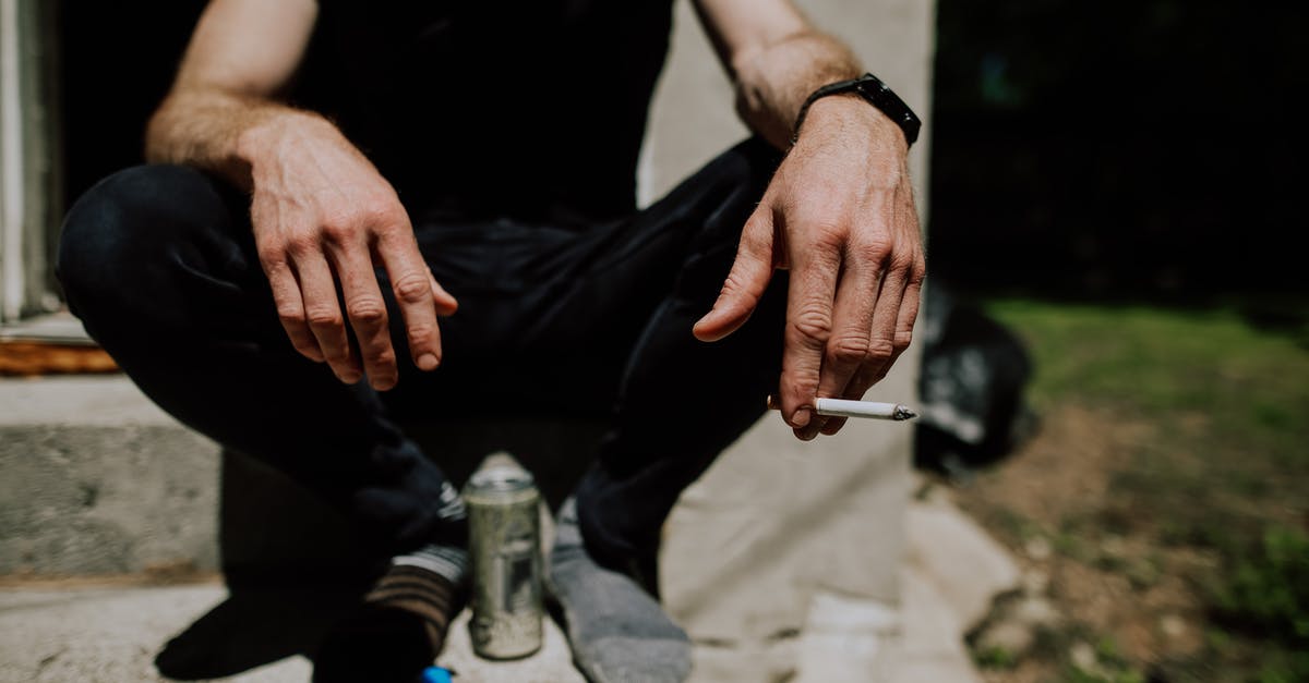 Bringing nicotine e-liquids to Australia - Crop man sitting on steps with cigarette in hand Bringing nicotine e-liquids to Australia - Crop man sitting on steps with cigarette in hand