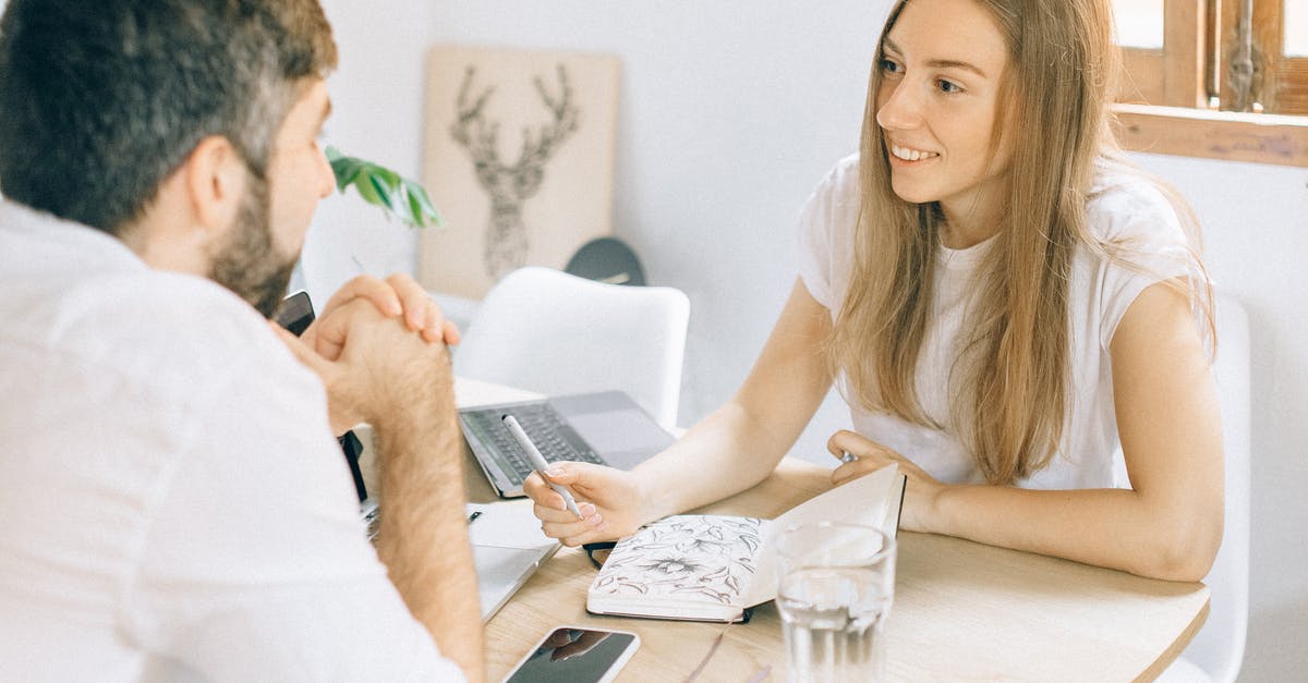 Bringing one cell phone from US to India for personal use, is this allowed? [duplicate] - Man and Woman Sitting at Table Using Laptop Computer