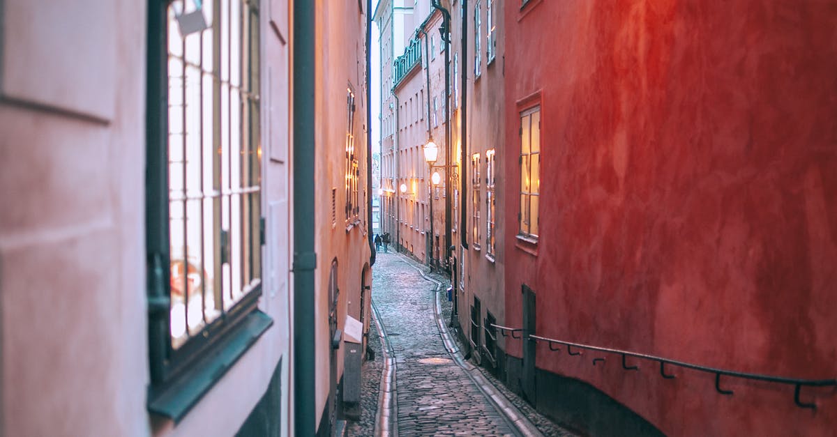 Build the ecologically most sustainable travel route in Europe oneself - Narrow cobblestone pedestrian passage between old apartment buildings with burning electric lights in windows at twilight