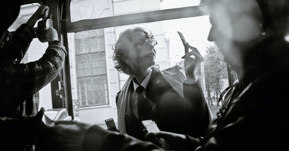 Bus from Zabaikalsk to Manzhouli, ticket price - Black and white of woman near crop male passenger using ticket puncher in retro vehicle during trip Bus from Zabaikalsk to Manzhouli, ticket price - Black and white of woman near crop male passenger using ticket puncher in retro vehicle during trip