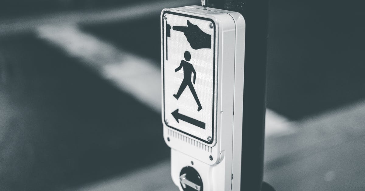Button for pedestrian traffic lights in Germany - Black and white of pedestrian crosswalk call button placed on city street against asphalt road in evening time Button for pedestrian traffic lights in Germany - Black and white of pedestrian crosswalk call button placed on city street against asphalt road in evening time