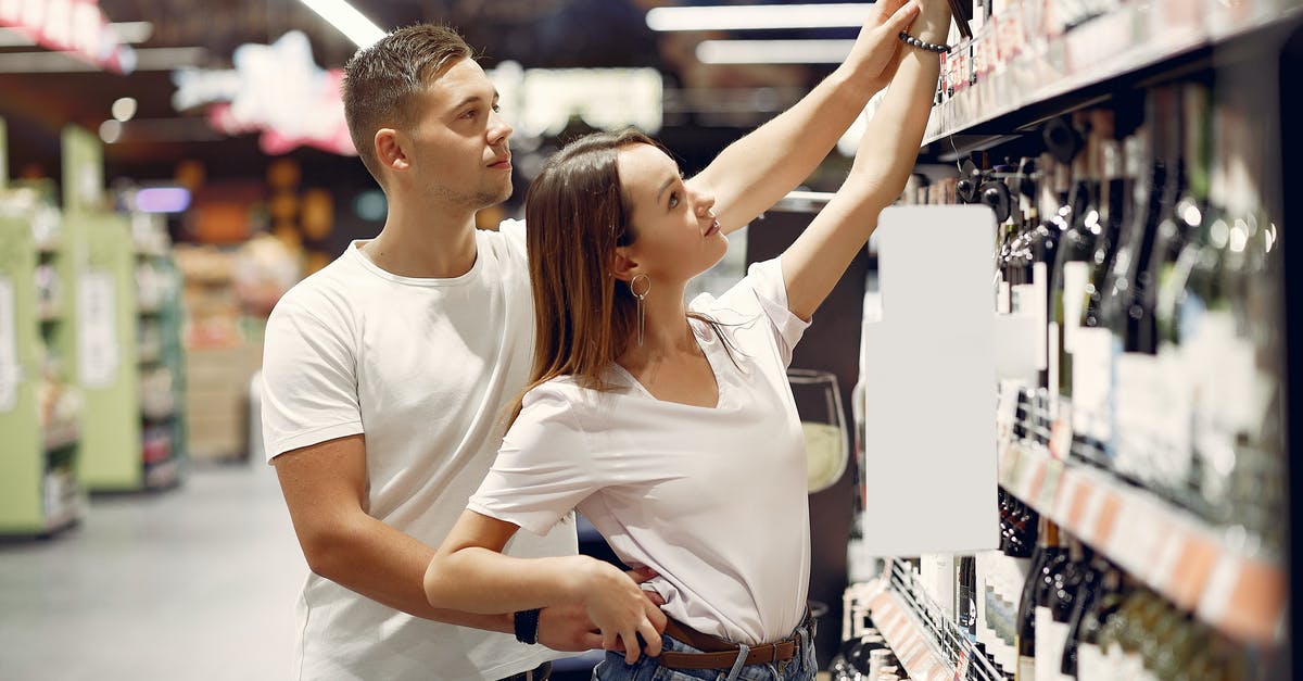Buy alcohol duty-free or in US? - Young couple choosing food in grocery store Buy alcohol duty-free or in US? - Young couple choosing food in grocery store