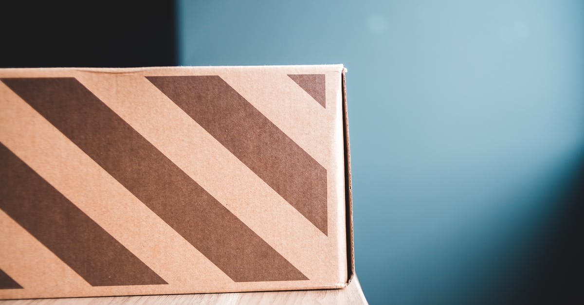 Buy and send postcard from Toluca, Mexico? - Closeup of carton box with stripes on wooden table against gray wall in apartment Buy and send postcard from Toluca, Mexico? - Closeup of carton box with stripes on wooden table against gray wall in apartment