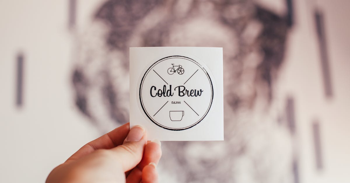 Buying Crit'air environment badge at short notice - Unrecognizable person demonstrating coffee shop badge with Cold Brew inscription and creative design in hand while standing on blurred background Buying Crit'air environment badge at short notice - Unrecognizable person demonstrating coffee shop badge with Cold Brew inscription and creative design in hand while standing on blurred background