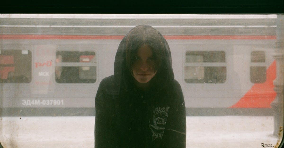 Buying ticket on Russian train - Hooded Unrecognizable Young Person Standing on Platform at Train Window Buying ticket on Russian train - Hooded Unrecognizable Young Person Standing on Platform at Train Window
