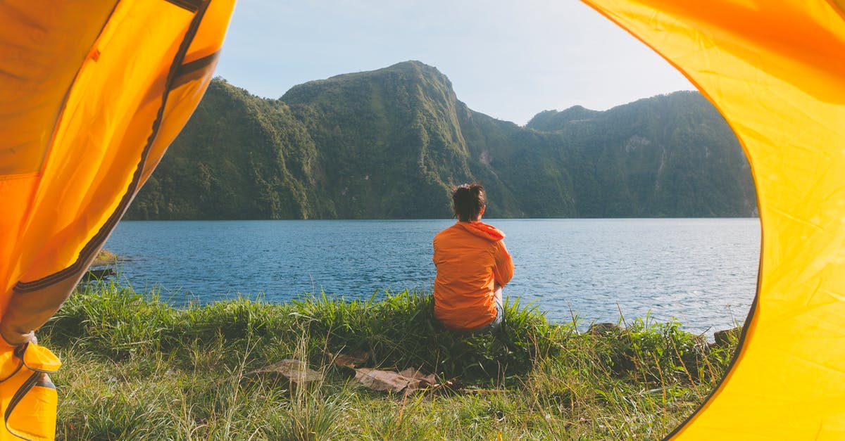 Cabins and camping options in Tatra mountains - Person Sitting on Grass Field Facing on Body of Water Cabins and camping options in Tatra mountains - Person Sitting on Grass Field Facing on Body of Water