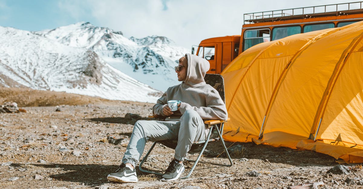Camping Equipment for Kruger - Full length of male camper sitting on folding chair next to tent in middle of mountain valley and enjoying views Camping Equipment for Kruger - Full length of male camper sitting on folding chair next to tent in middle of mountain valley and enjoying views