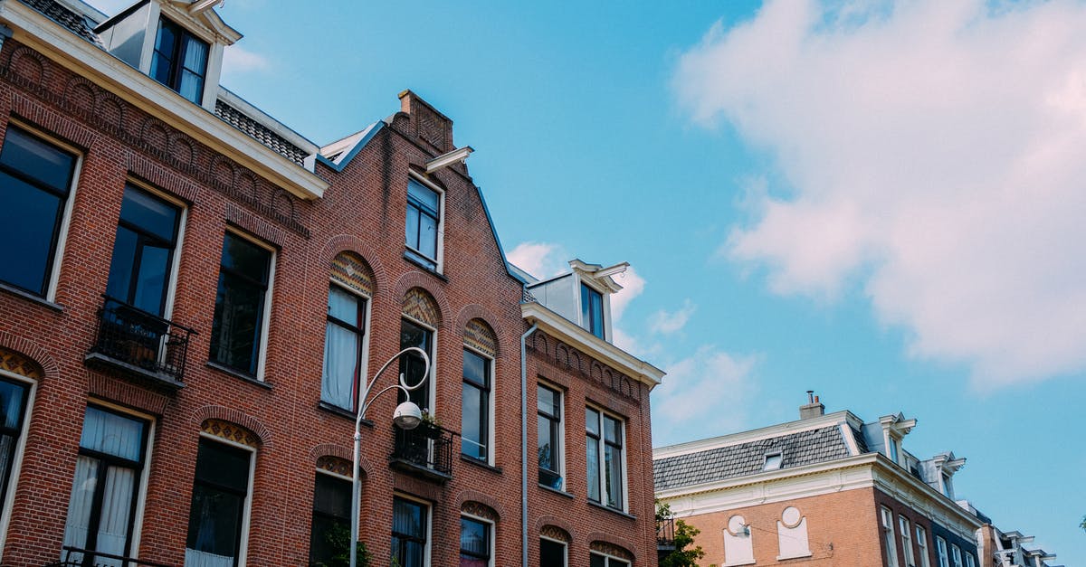Can a Malaysian citizen enter the Schengen area a day earlier than their visa-free date? [duplicate] - Low angle brick facade of old residential building with balconies and tile roof against blue sky on sunny day