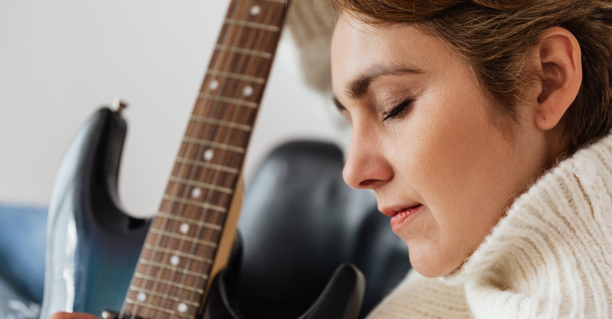 Can a musician missing their instrument at home visit music shops purely to play in-store, not to buy? [closed] - Calm woman playing electric guitar with closed eyes