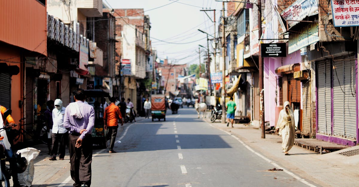 Can a non-EU citizen travel freely within the Schengen area without passport? [duplicate] - Citizens walking along street with shabby buildings and tuc tuc bikes parked on roadside in poor area of Asian town on sunny weather