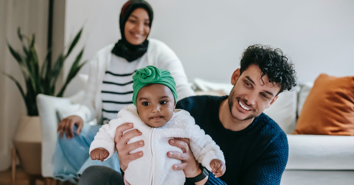 Can a non-parent file for OCI or Indian visa for non-Indian child? - Happy diverse parents smiling while playing with cute baby in living room Can a non-parent file for OCI or Indian visa for non-Indian child? - Happy diverse parents smiling while playing with cute baby in living room