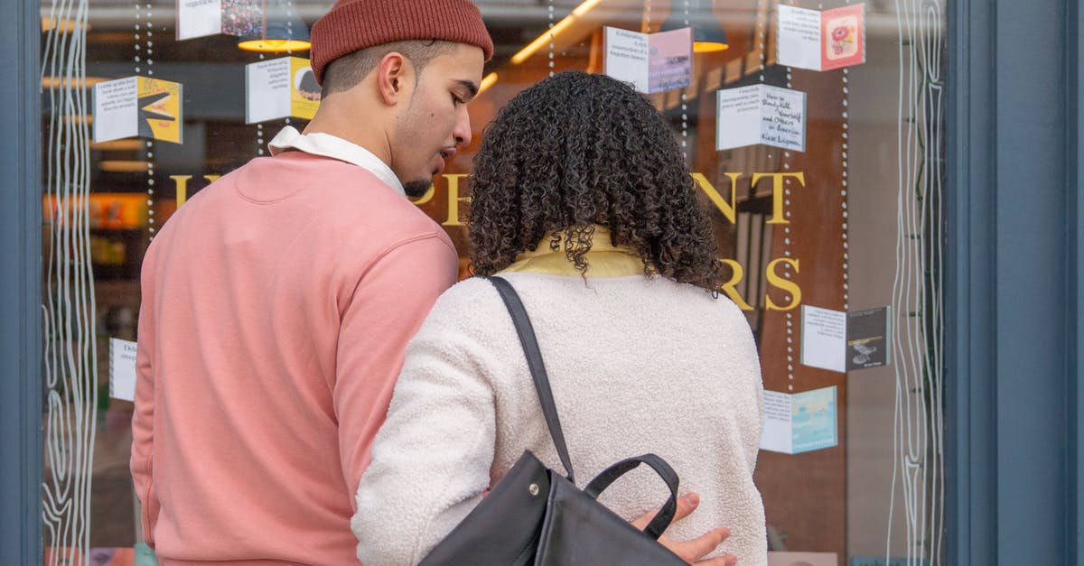 Can an overstayed student visa affect when applying another student visa for another country? [closed] - Back view of young Hispanic couple in stylish clothes cuddling while standing near glass showcase of bookstore during weekend in city