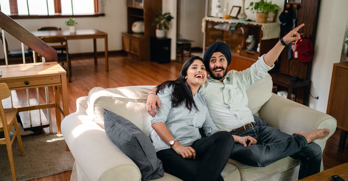 Can having a second wife affect my Australian visa processing/stay? - From above of smiling Indian man and woman in casual wear enjoying free time and chilling on sofa in modern light room while boyfriend pointing finger side up Can having a second wife affect my Australian visa processing/stay? - From above of smiling Indian man and woman in casual wear enjoying free time and chilling on sofa in modern light room while boyfriend pointing finger side up