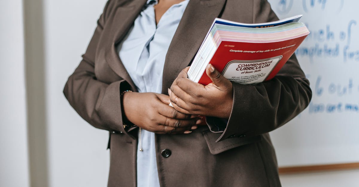Can I attend a short training course for medical professionals on a UK standard visitor visa? - Anonymous black female tutor with books standing near whiteboard at school