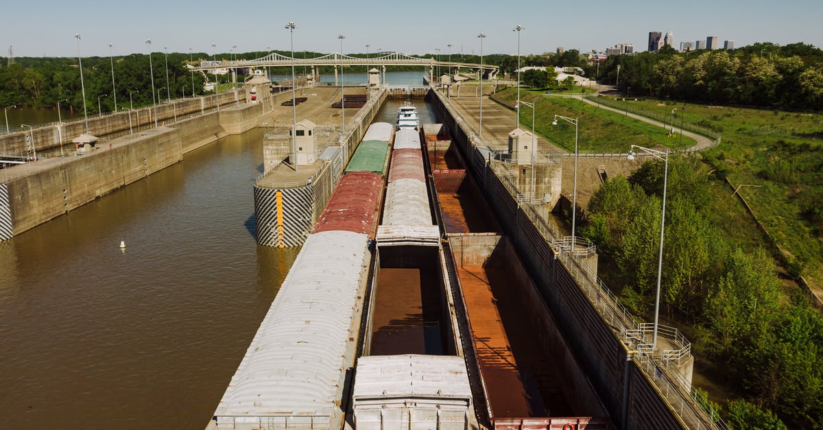Can I carry a mercury-vapor quartz lamp on a flight from Moscow to Sydney? - From above of old barge carrying heavy metal containers on canal between growing trees in city port under sky Can I carry a mercury-vapor quartz lamp on a flight from Moscow to Sydney? - From above of old barge carrying heavy metal containers on canal between growing trees in city port under sky