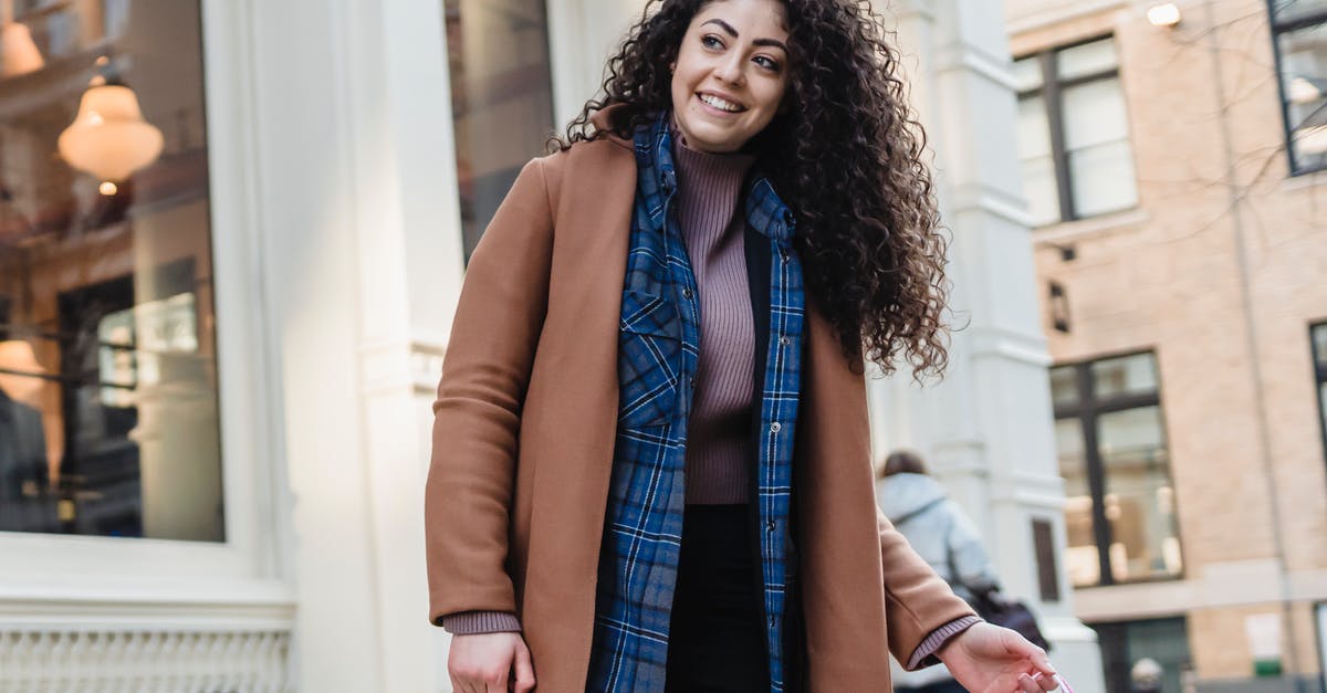 Can I carry a watch as a gift in my carry-on luggage when flying from Kolkata to Chennai? [duplicate] - Low angle of positive ethnic female in coat above casual wear standing with bright gift bags on sidewalk and looking away