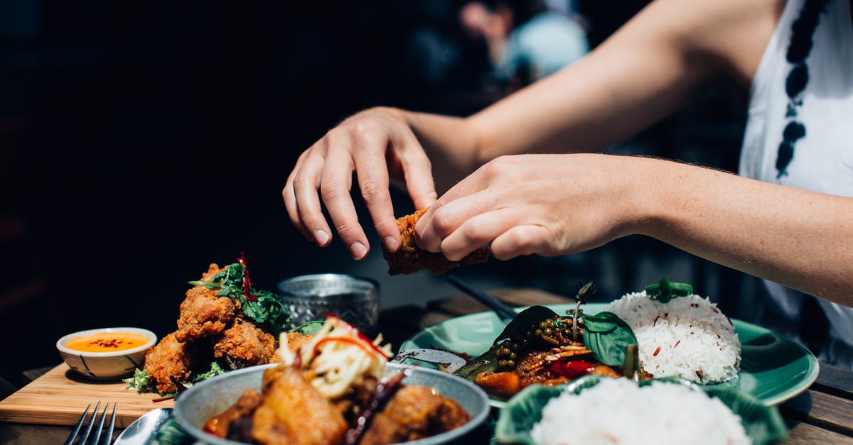 Can I carry fried rice and dried chicken preparation? - Person Holding Piece of Fried Chicken Above Plate with Food Can I carry fried rice and dried chicken preparation? - Person Holding Piece of Fried Chicken Above Plate with Food