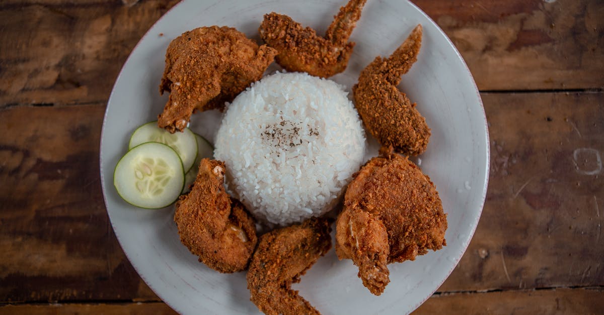 Can I carry fried rice and dried chicken preparation? - Top view of appetizing golden chicken wings with cooked rice and cucumber slices on wooden table Can I carry fried rice and dried chicken preparation? - Top view of appetizing golden chicken wings with cooked rice and cucumber slices on wooden table