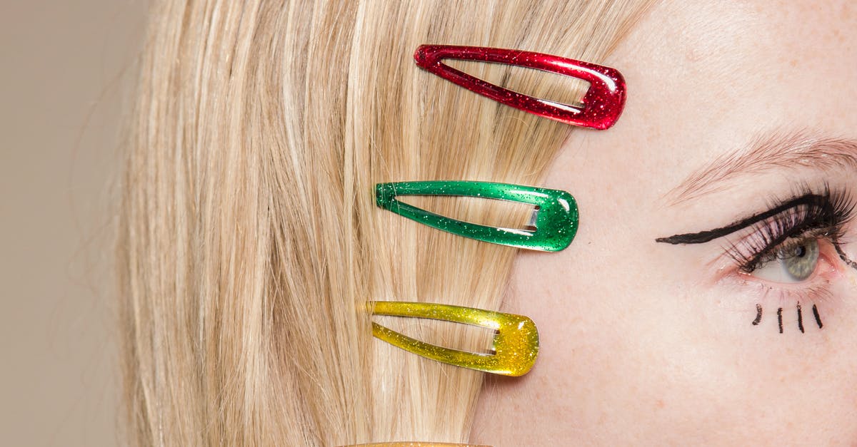 Can I carry my makeup like kajal eyeliner hair serum on my check in bags? - Crop anonymous female with red green and yellow hair clips on head on beige background Can I carry my makeup like kajal eyeliner hair serum on my check in bags? - Crop anonymous female with red green and yellow hair clips on head on beige background