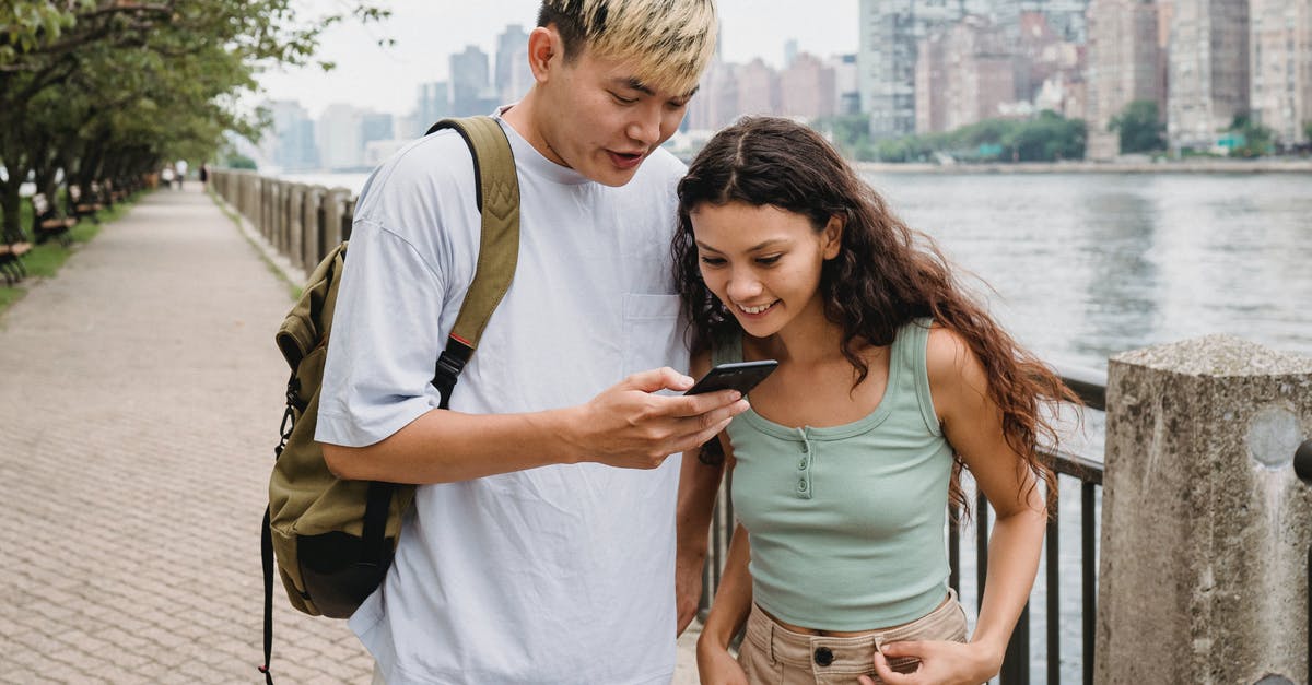 can I change the date of travel to the UK after filling out the online form? [duplicate] - Cheerful young ethnic lady with long hair smiling and watching photos on smartphone with boyfriend while standing on promenade near river in city