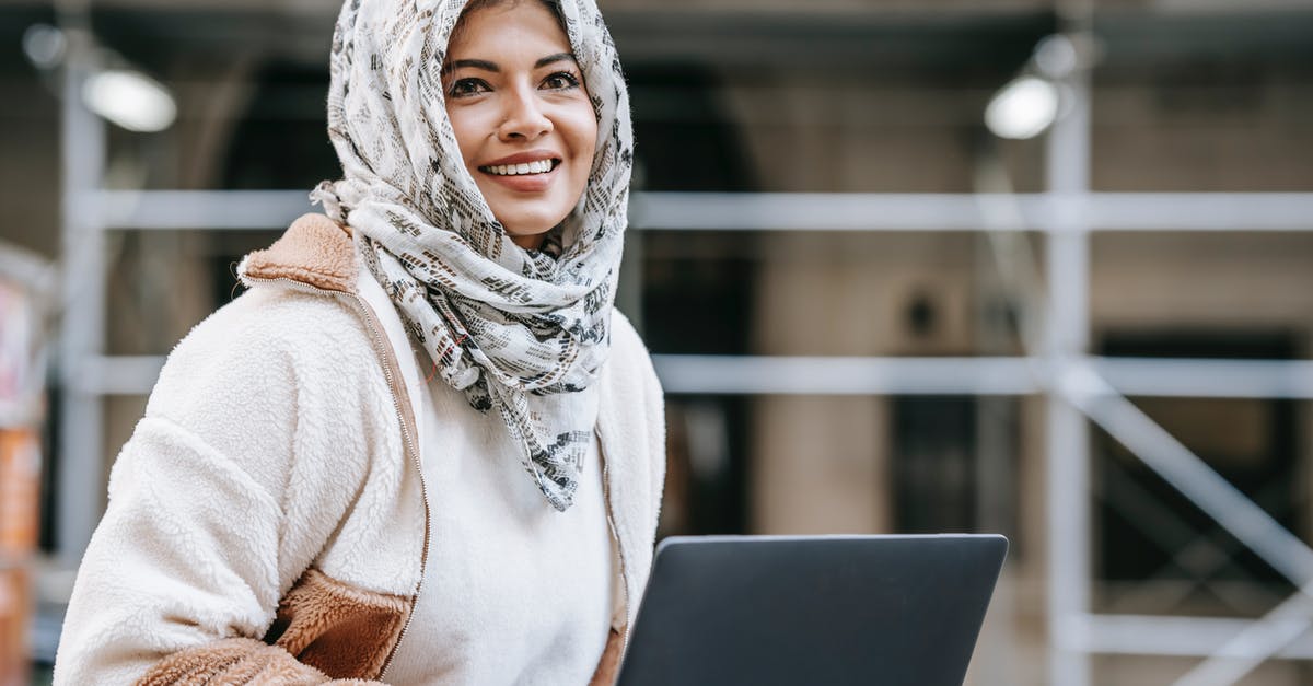 Can I communicate via an encrypted connection in United Arab Emirates? - Joyful young Arab female freelancer in casual outfit and hijab smiling while working remotely on netbook on city street Can I communicate via an encrypted connection in United Arab Emirates? - Joyful young Arab female freelancer in casual outfit and hijab smiling while working remotely on netbook on city street