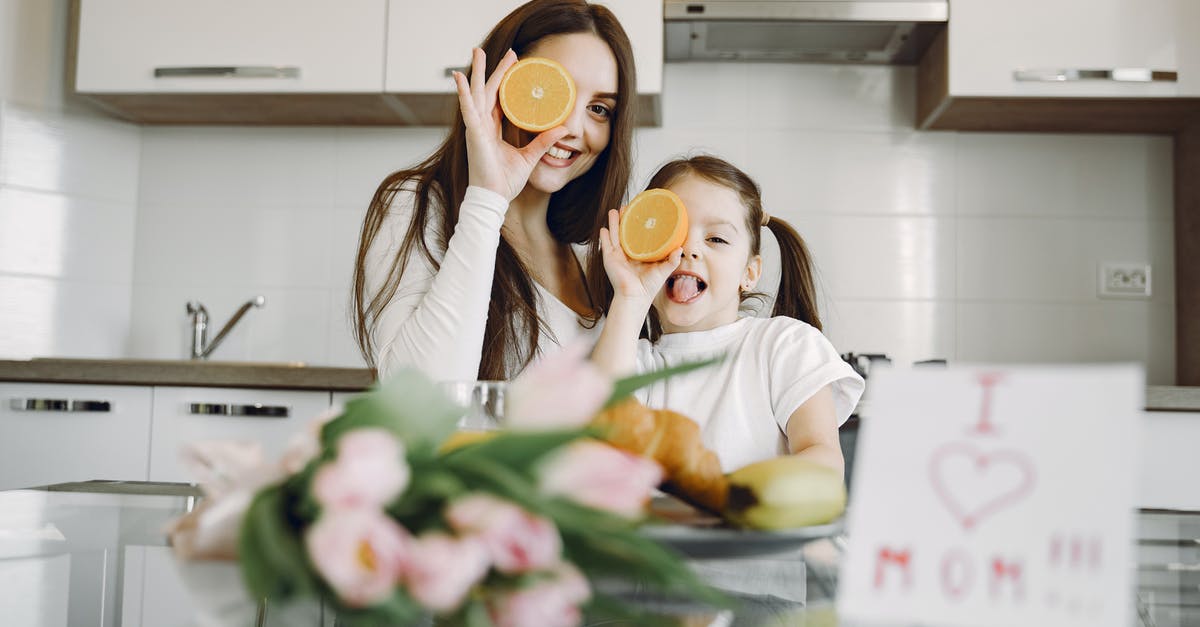 Can I eat only a crème brûlée in Paris? - From below of cheerful mother and daughter in domestic clothes smiling and playing with oranges while sitting together at table with bouquet of tulip and drawing of child Can I eat only a crème brûlée in Paris? - From below of cheerful mother and daughter in domestic clothes smiling and playing with oranges while sitting together at table with bouquet of tulip and drawing of child