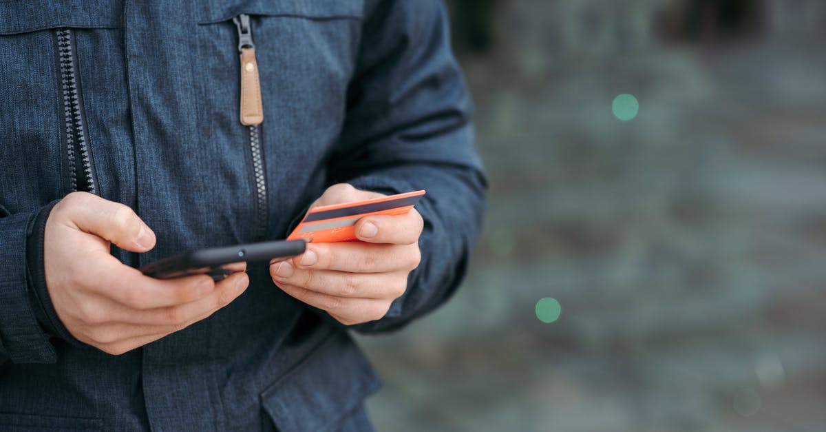 Can I enter Kosovo with EU ID card? - Man holding credit card and browsing smartphone on street