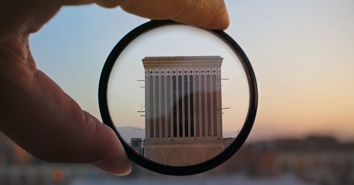 Can I fly with glass photographic filters in my hand luggage? - Person Holding Magnifying Glass Showing Building