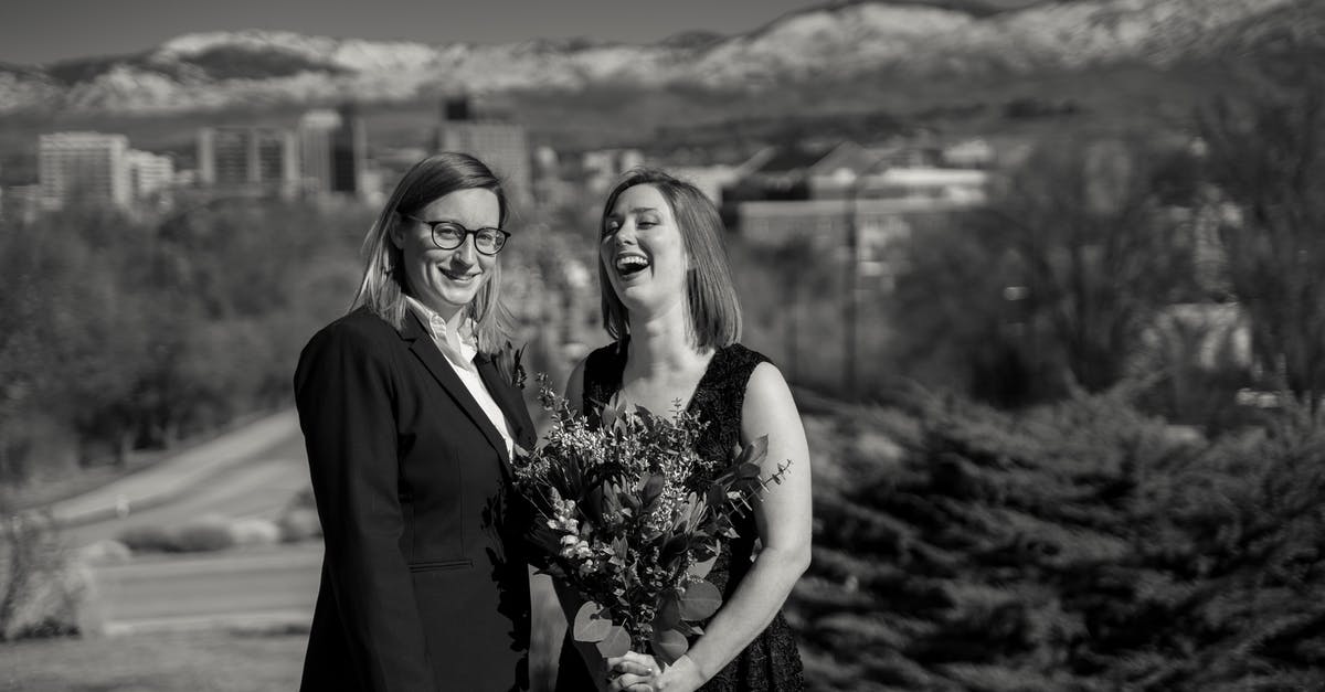 Can I have a same sex marriage to my partner who is overseas? [duplicate] - Black and white cheerful married lesbian couple in elegant outfits smiling and standing together against highlands