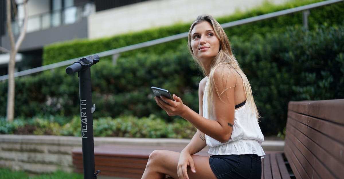 Can I hire a mobility scooter in Dortmund? - Woman in White Tank Top and Black Shorts Sitting on Brown Wooden Bench