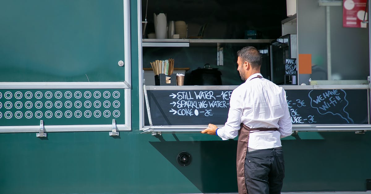 Can I leave the Schengen area and go back if I receive an employee card? [closed] - Back view of male seller wearing apron preparing food truck with menu written on board