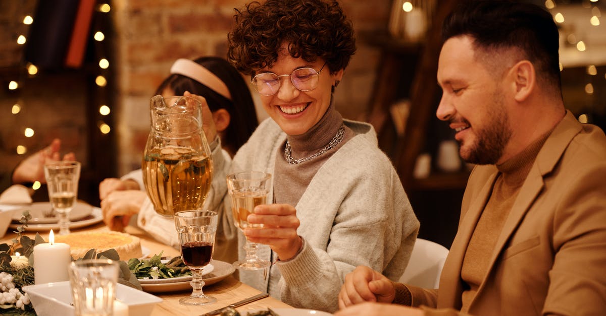 Can I meet up with friends at a layover such as Istanbul without getting a transit visa? - Woman in Gray Sweater Sitting Beside Man in Brown Blazer