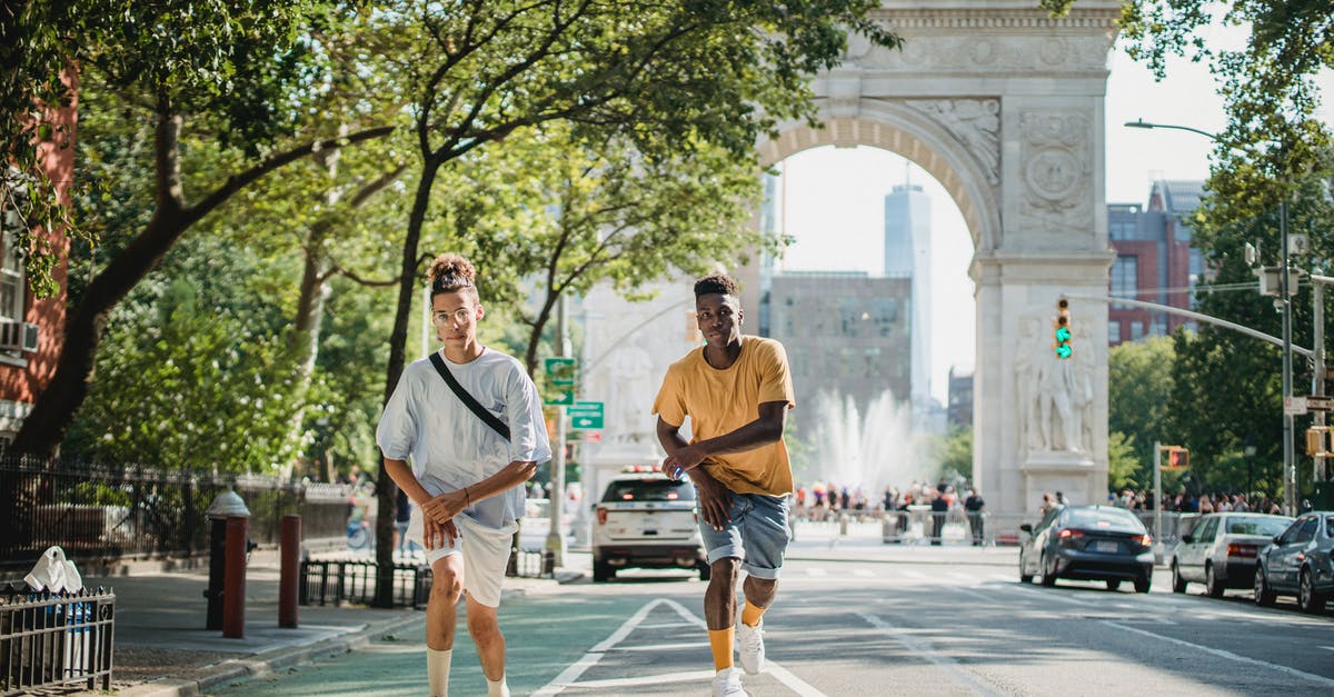 Can I move to Germany from the US during COVID? - Full body of serious multiethnic male skateboarders riding skateboards along road against Triumphal Arch in New York