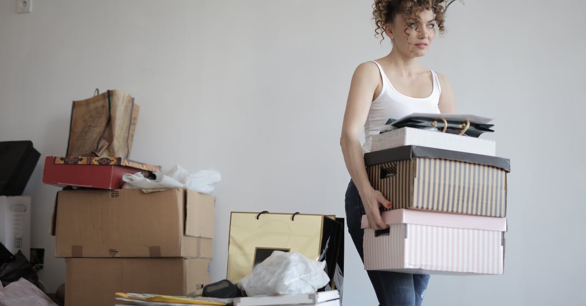 Can I pack a cardboard box as checked luggage? - Concentrated woman carrying stack of cardboard boxes for relocation Can I pack a cardboard box as checked luggage? - Concentrated woman carrying stack of cardboard boxes for relocation