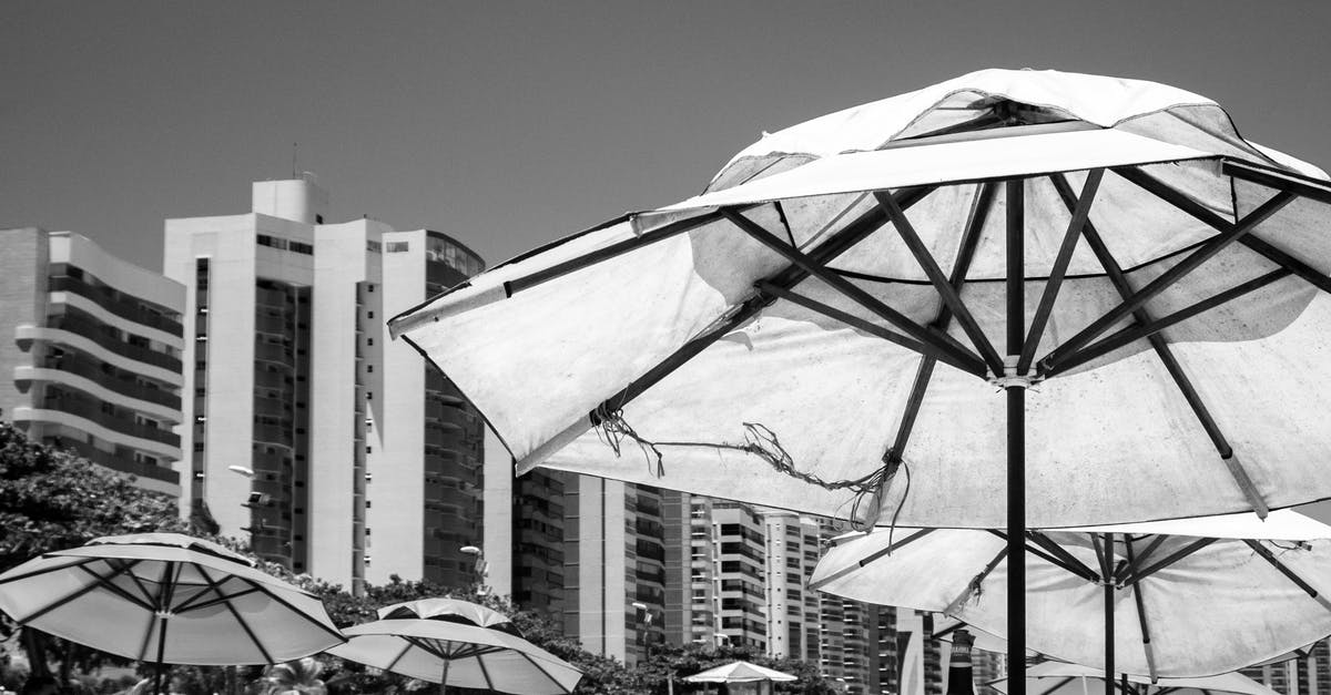Can I reserve a beach spot by leaving an umbrella and lounge chair overnight (Italy)? - Black and white of umbrellas on terrace of resort hotel with tables and chairs near beach Can I reserve a beach spot by leaving an umbrella and lounge chair overnight (Italy)? - Black and white of umbrellas on terrace of resort hotel with tables and chairs near beach