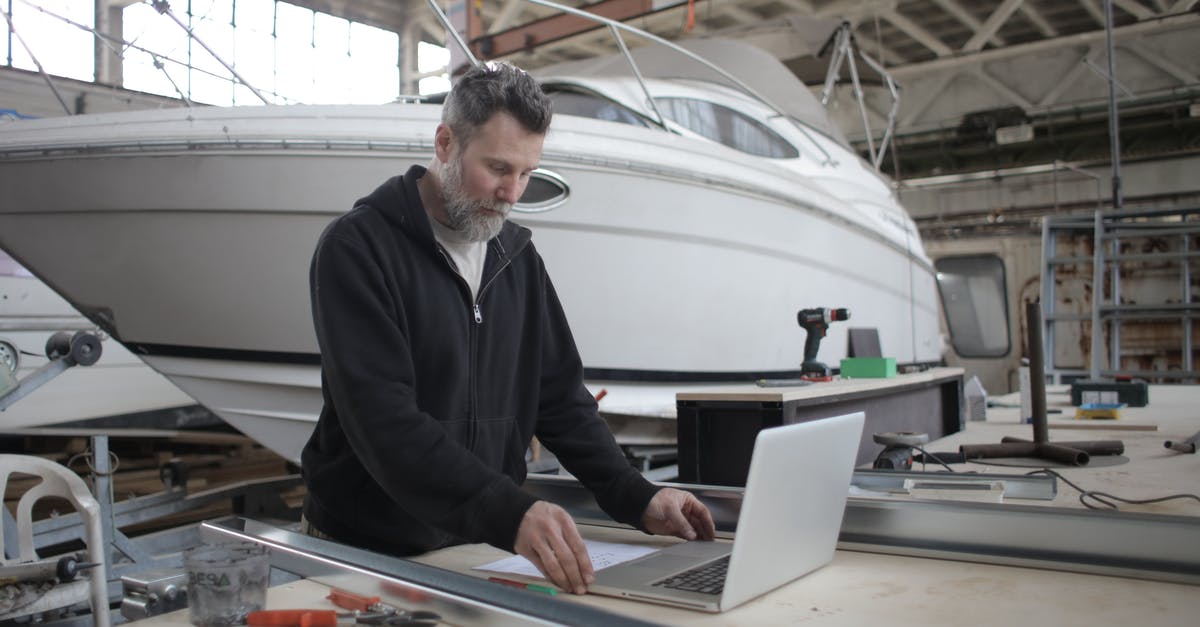 Can I ship a laptop to people in Canada and pick it up off them in Ireland? - Thoughtful adult worker using laptop while working with metal parts near boat in workshop Can I ship a laptop to people in Canada and pick it up off them in Ireland? - Thoughtful adult worker using laptop while working with metal parts near boat in workshop