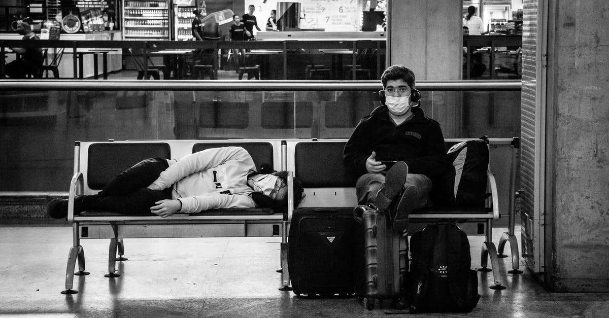 Can I sleep overnight at Stansted Airport? - Anonymous tourists in masks on bench in airport Can I sleep overnight at Stansted Airport? - Anonymous tourists in masks on bench in airport