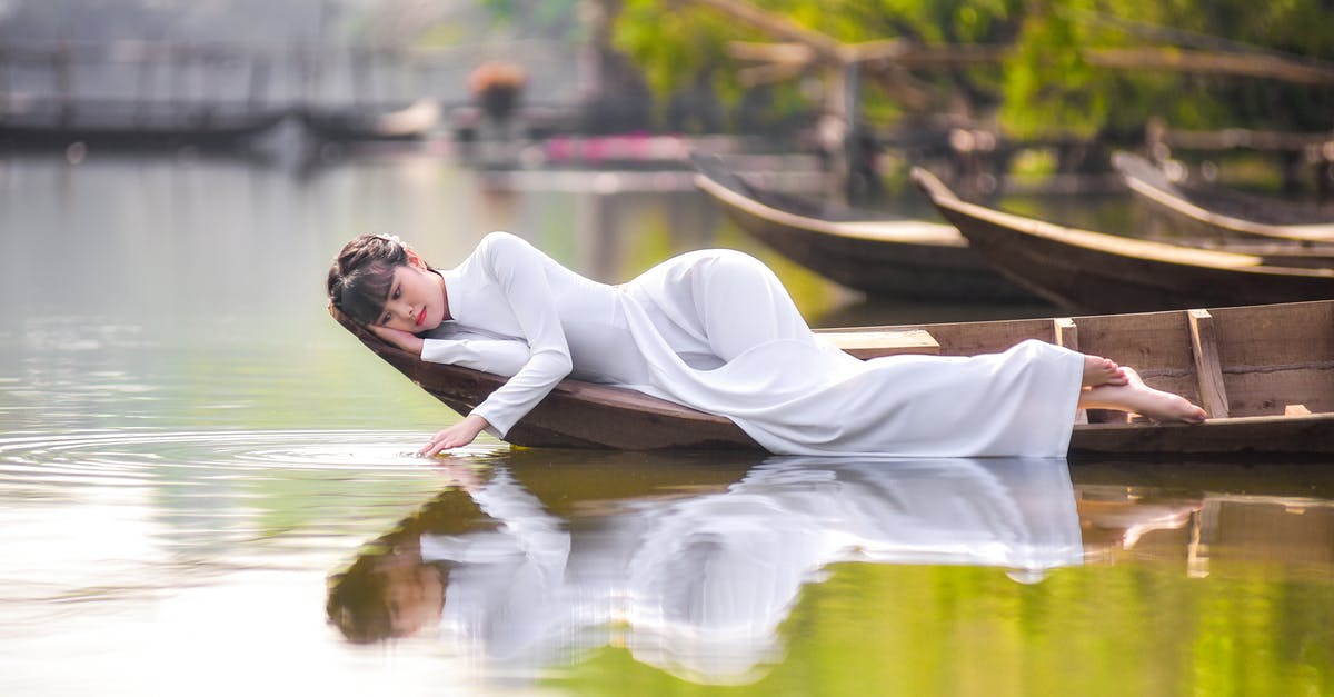 Can I take a boat down the Mosel river from the vicinity of Trier to Koblenz - Woman in White Robe Sitting on Brown Wooden Boat on River