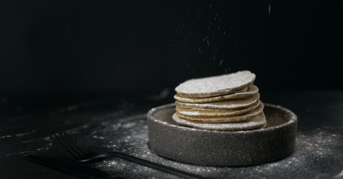 Can I take a metal knife and fork through airport security? - Delicious sweet pancakes placed in baking dish near metal fork and knife on table on black background