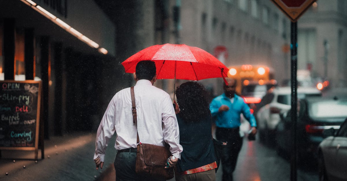 Can I take the 00:05 bus back with a rail-air day return? - Man in White Dress Shirt and Blue Denim Jeans Holding Red Umbrella
