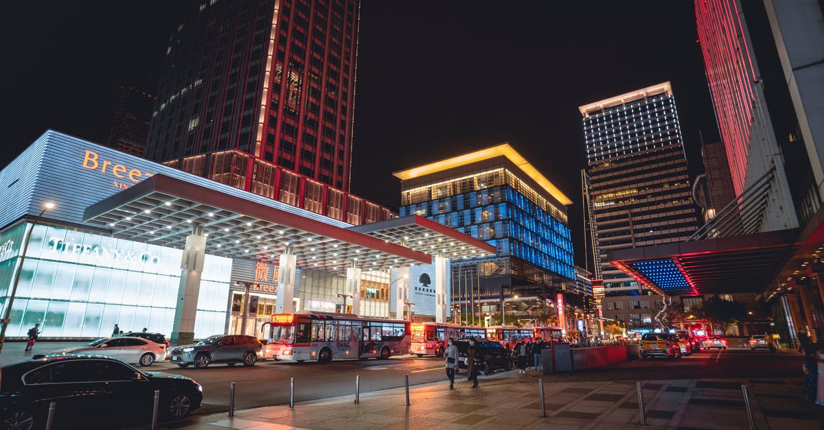 Can I take the 105 bus into Heathrow Central Bus Station? - Town with illuminated buildings and skyscrapers near road with cars and buses near pavement with people under dark cloudless sky at night